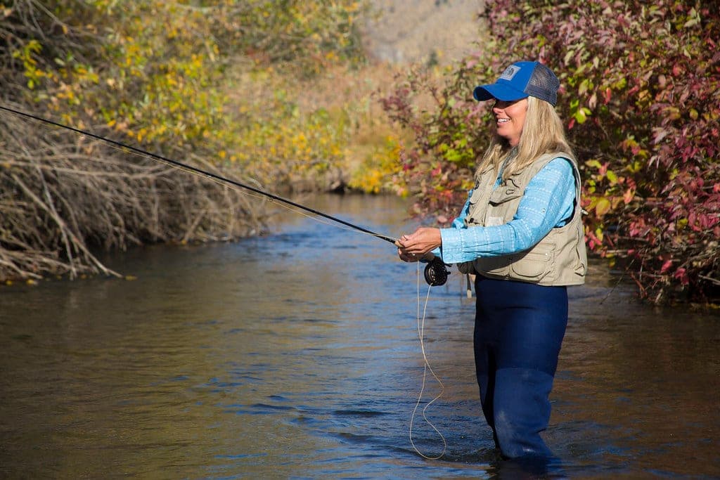 An angler fly fishing a shallow river reach in flat morning light